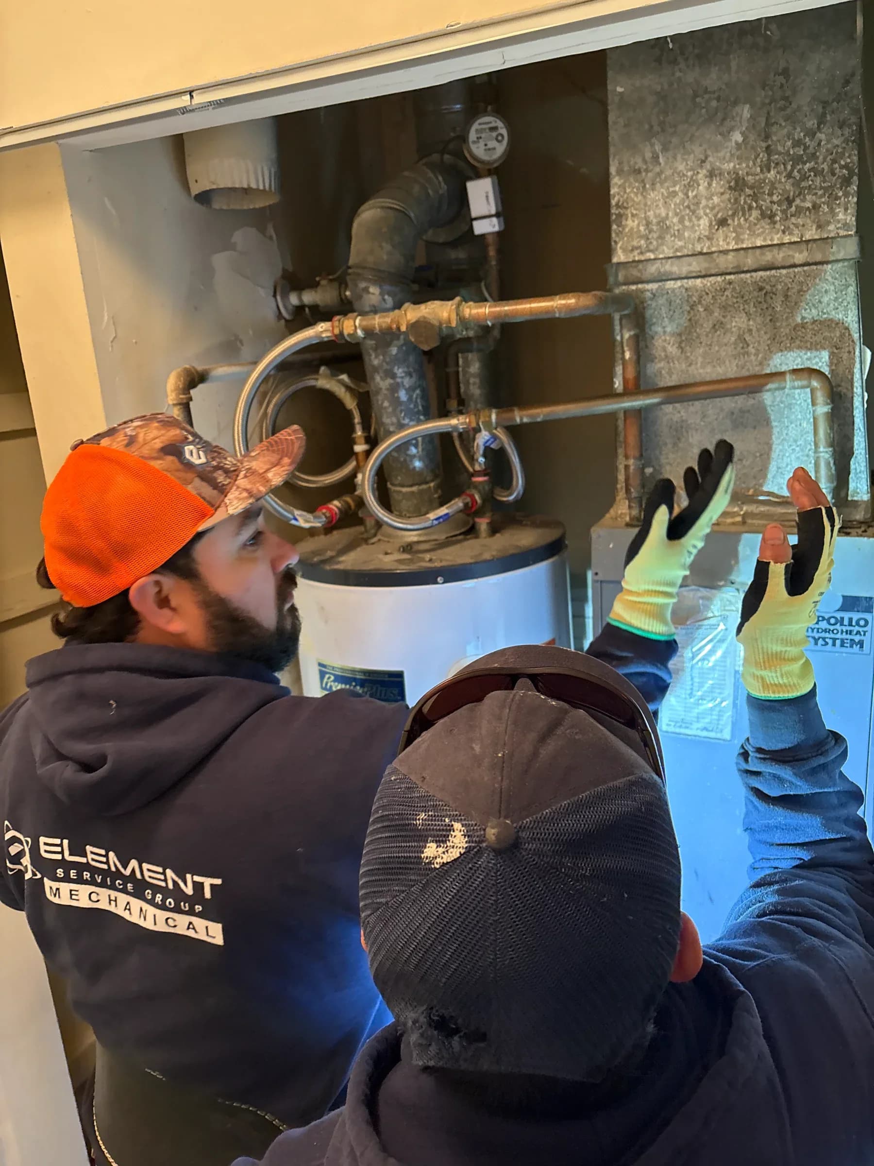 HVAC technicians inspecting a water heater system during routine maintenance.