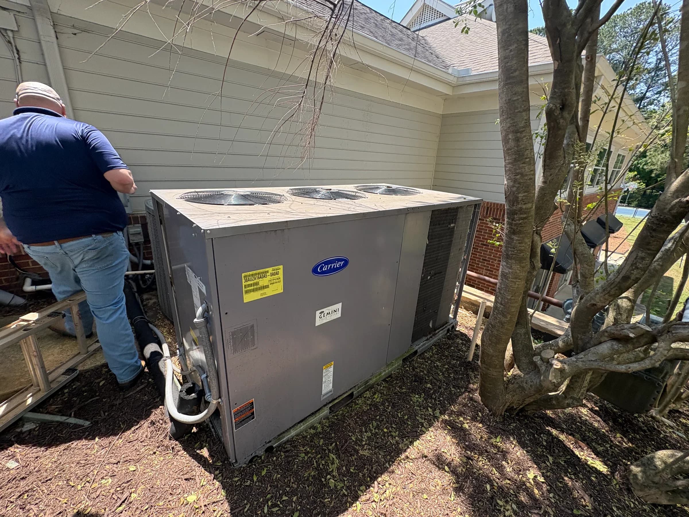 HVAC technician servicing a Carrier outdoor unit in residential backyard settings.