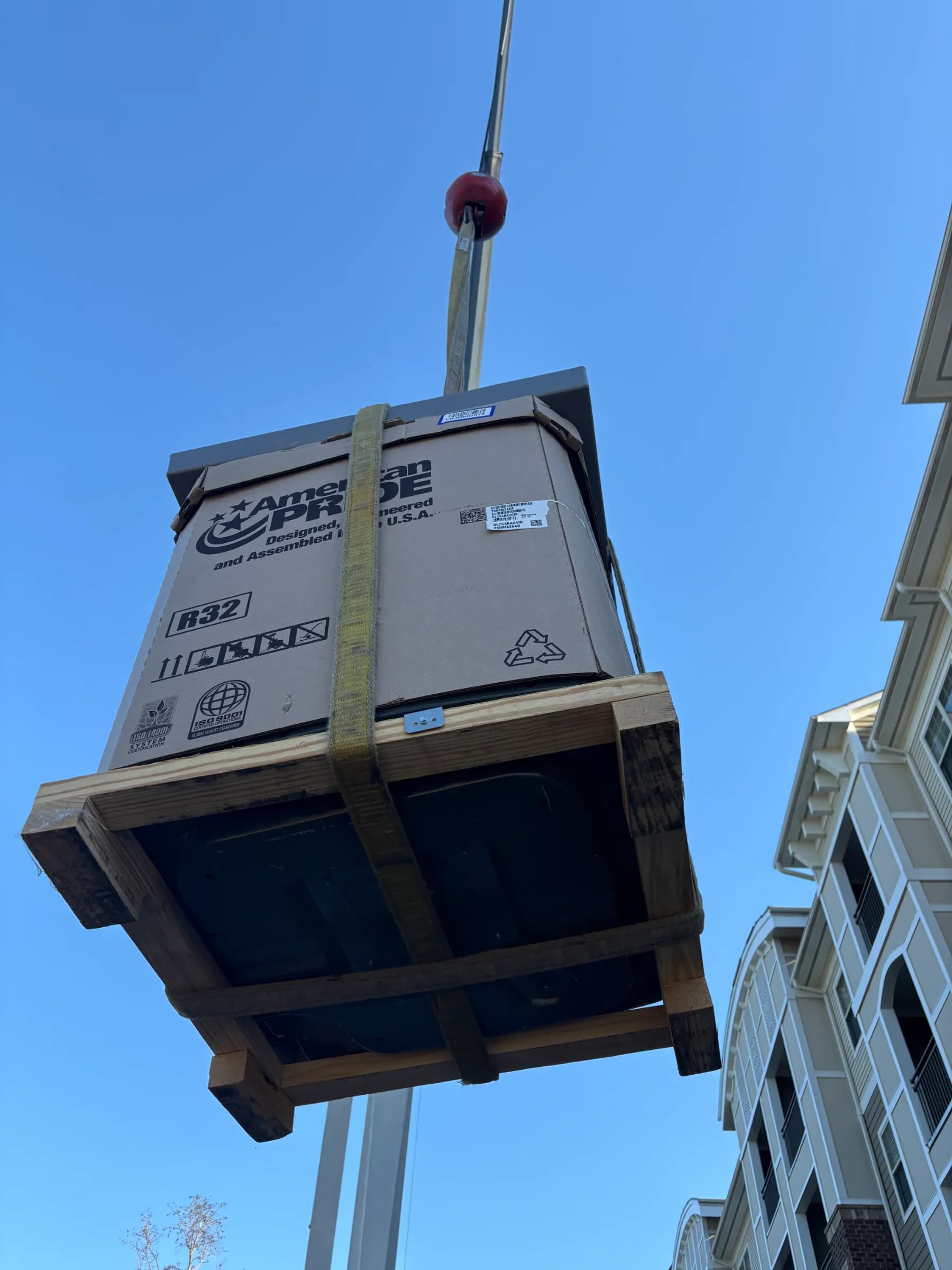 HVAC unit being lifted for installation at a residential building